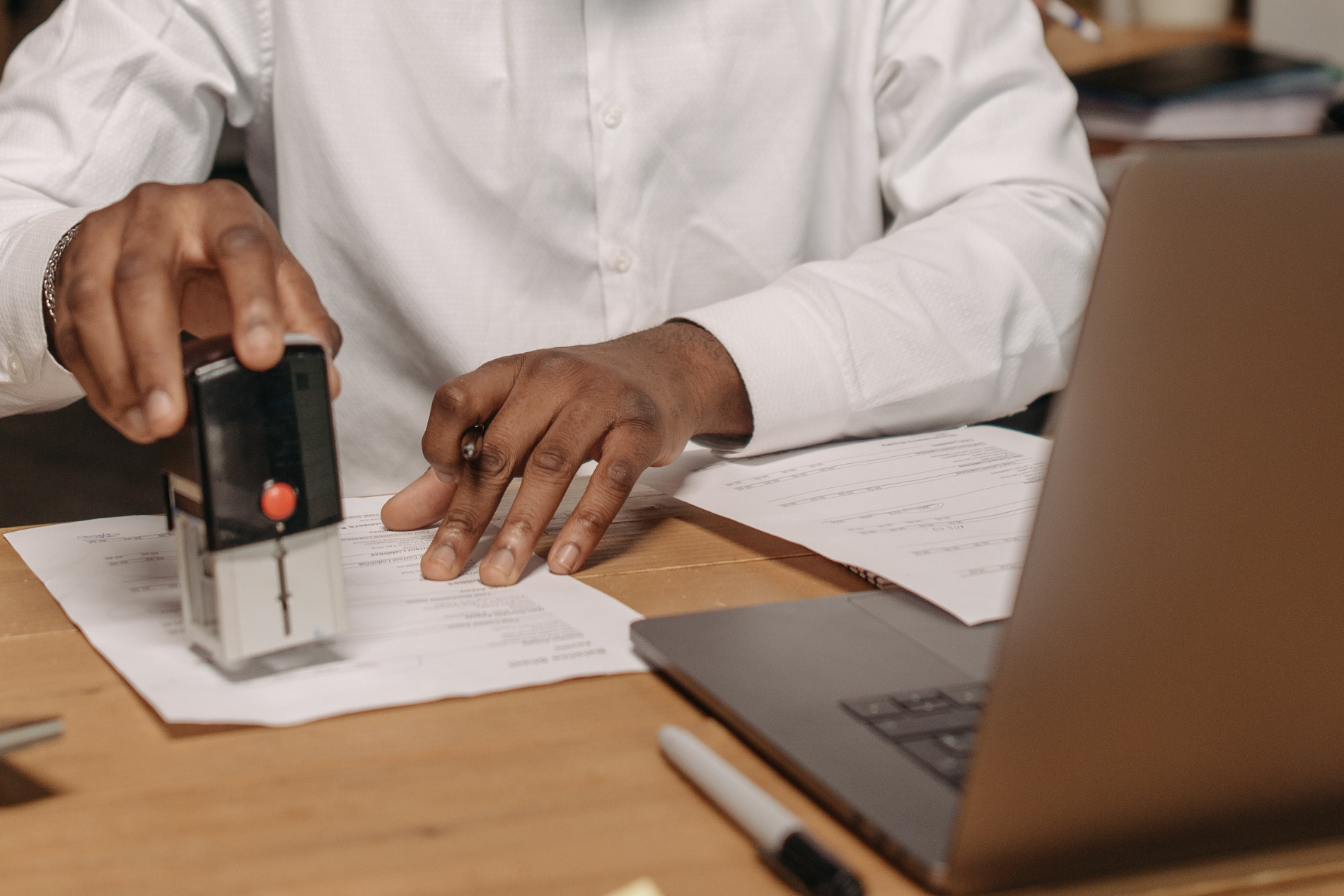 a professional man stamps a form next to a laptop computer