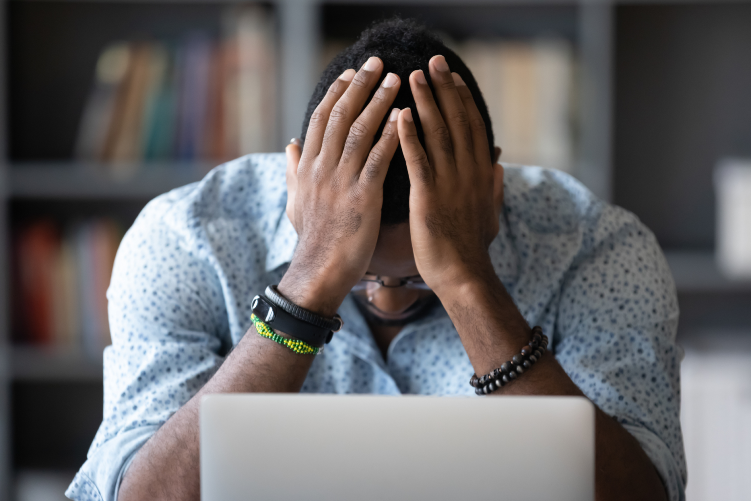 a frustrated man with his head in his hands at a laptop computer