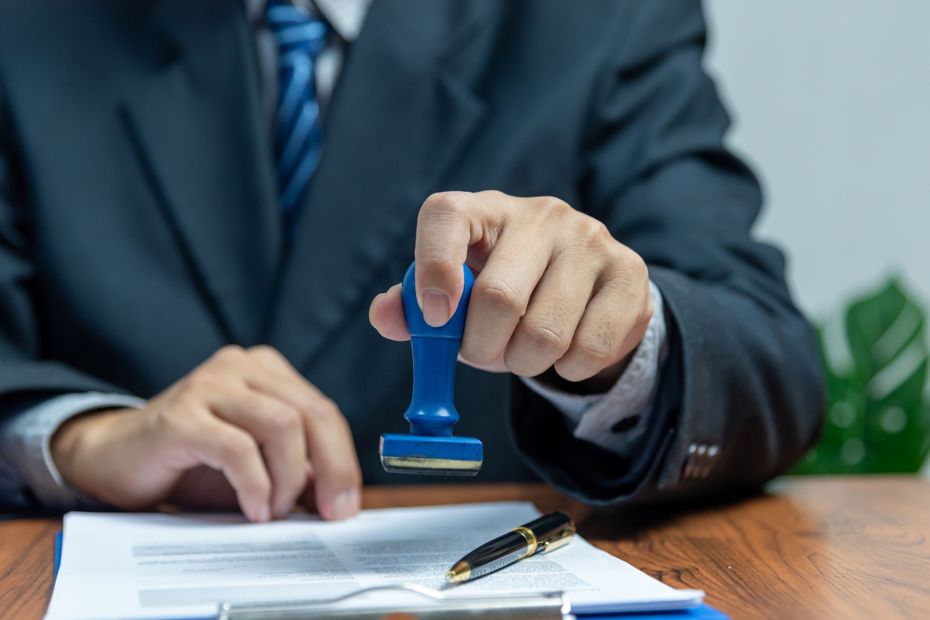a suited business professional stamps a signed document in approval