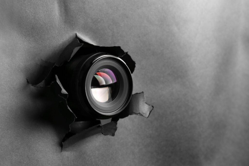 a camera lense poking through a black paper screen